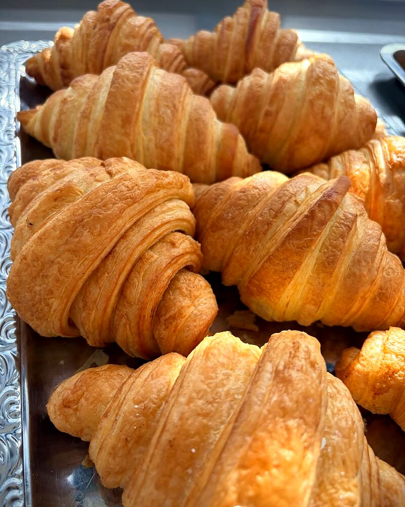 Croissante cu unt proaspăt coapte, pe tavă de inox